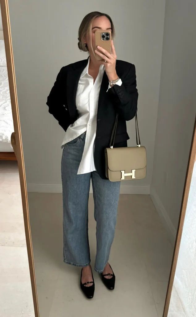Black fitted blazer styled with an untucked white button-down shirt, light wash straight jeans, black Mary Jane flats, and a tan structured crossbody bag, mirror selfie