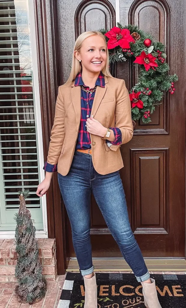 Petite blazer outfit with a fitted camel blazer layered over a navy and red plaid flannel shirt, dark skinny jeans cuffed at the ankle, and tan ankle boots