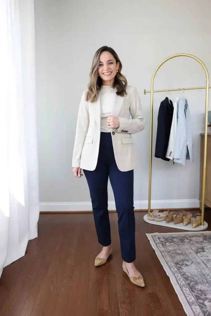 Petite woman in a cream plaid single-button blazer with navy cropped trousers and tan bow-detail pointed flats