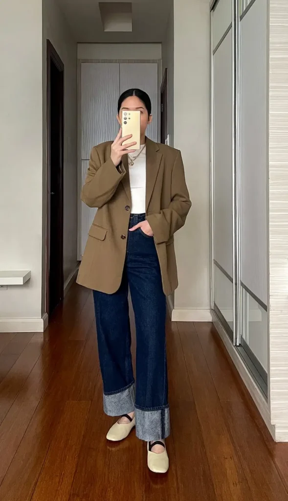 Petite blazer outfit with an oversized olive blazer worn open over a fitted white top, cuffed dark wide-leg jeans, cream Mary Jane flats, and a layered gold necklace
