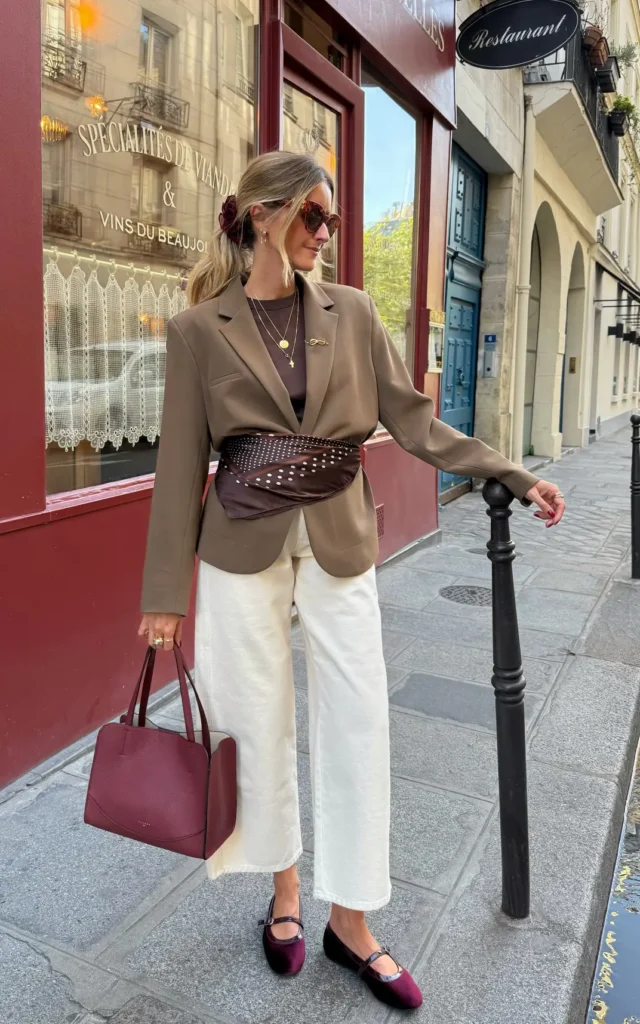 Tan oversized blazer cinched with a dark brown polka dot belt bag over cream wide-leg trousers and burgundy velvet Mary Jane flats, Paris street style
