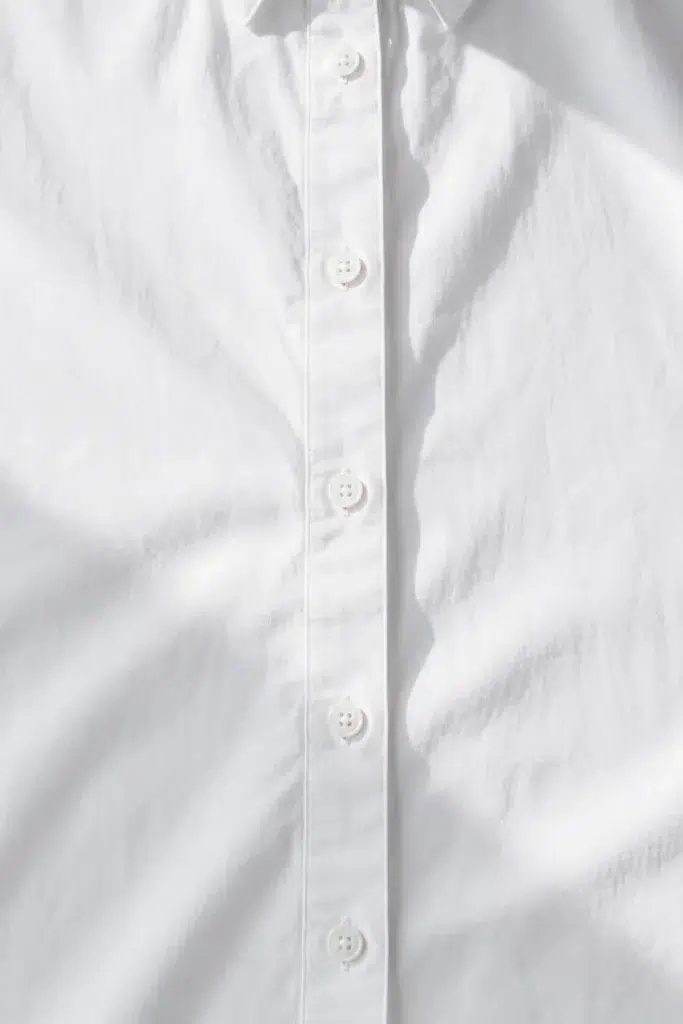 Extreme close-up of a white button-front shirt showing an evenly spaced vertical button placket