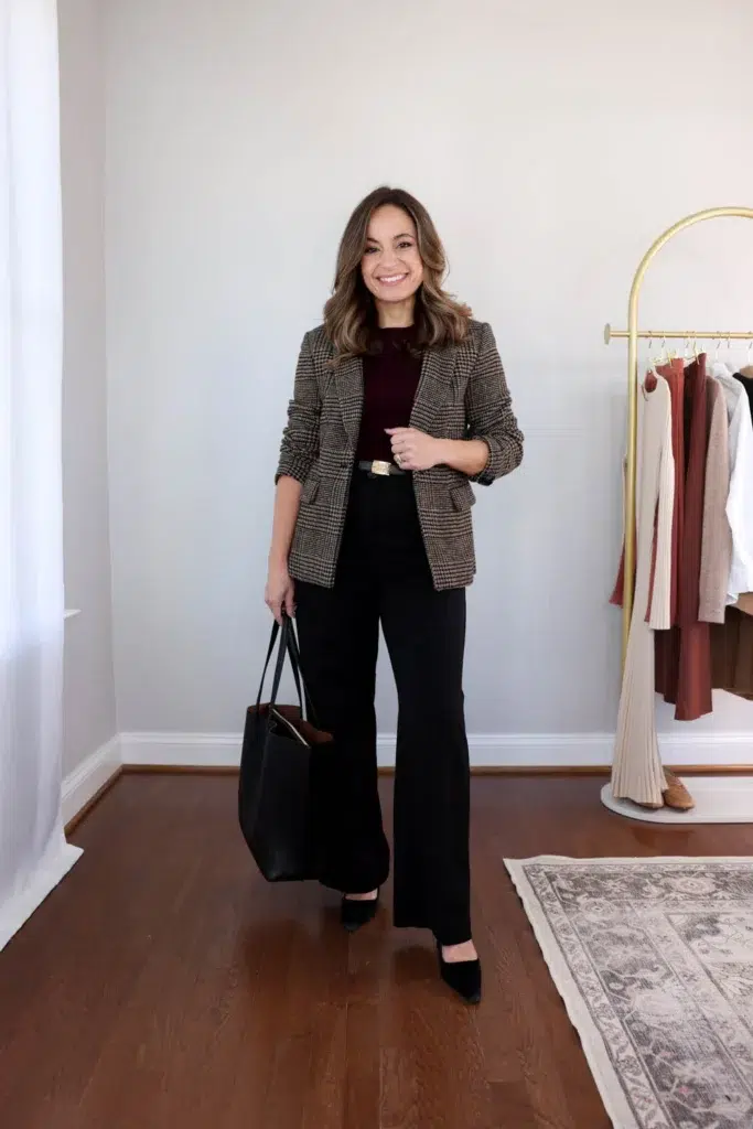 Woman in a brown houndstooth blazer over a black ribbed top and black wide-leg trousers with a black belt and tan pointed flats